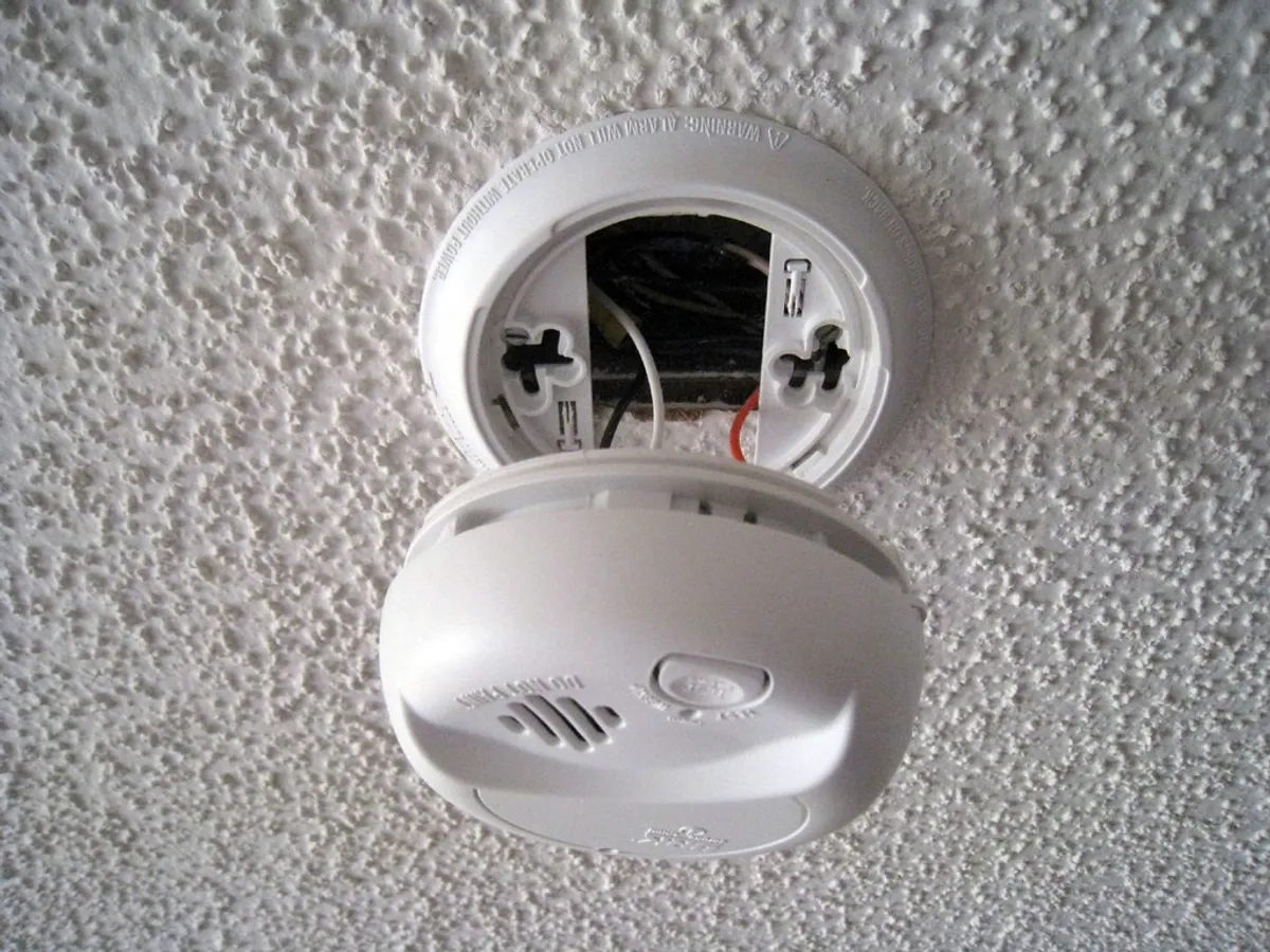 Smoke alarm being fitted to a ceiling base